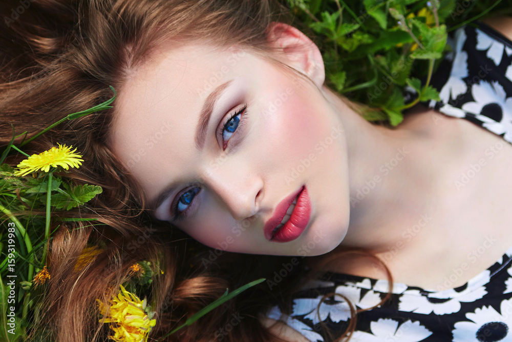 Beautiful young natural well-groomed girl lies on the grass with yellow ...