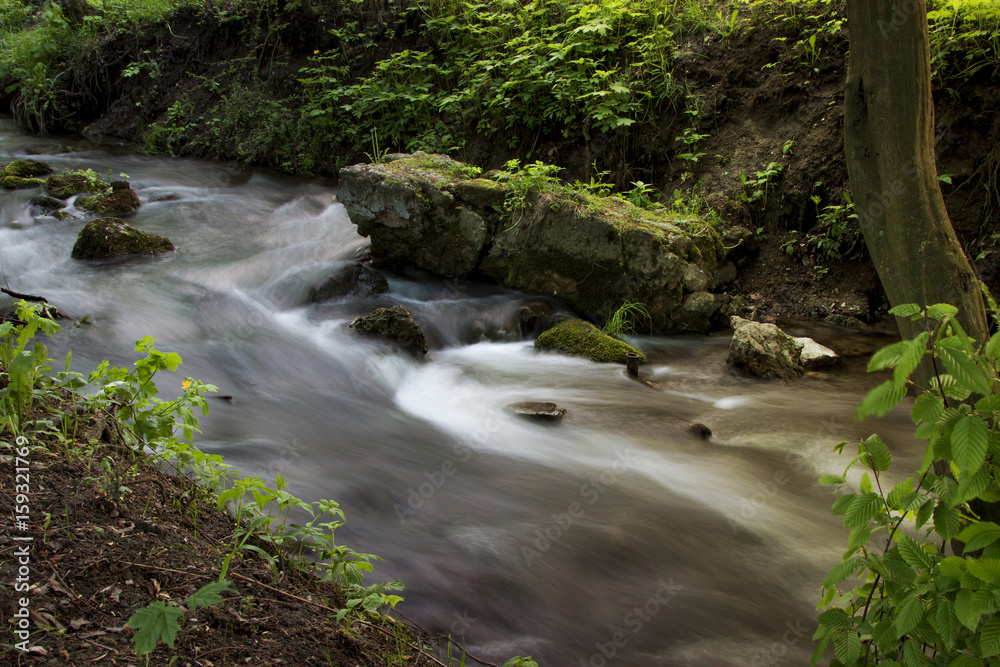 Forest stream running over mossy rocks in the morning . Long exposure Forest stream running over mossy rocks in the morning . Long exposure