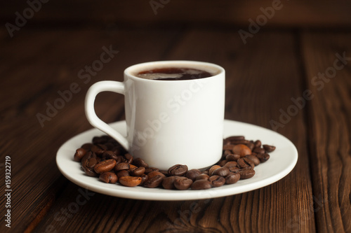 Coffee cup and coffee beans on wooden table. Front view