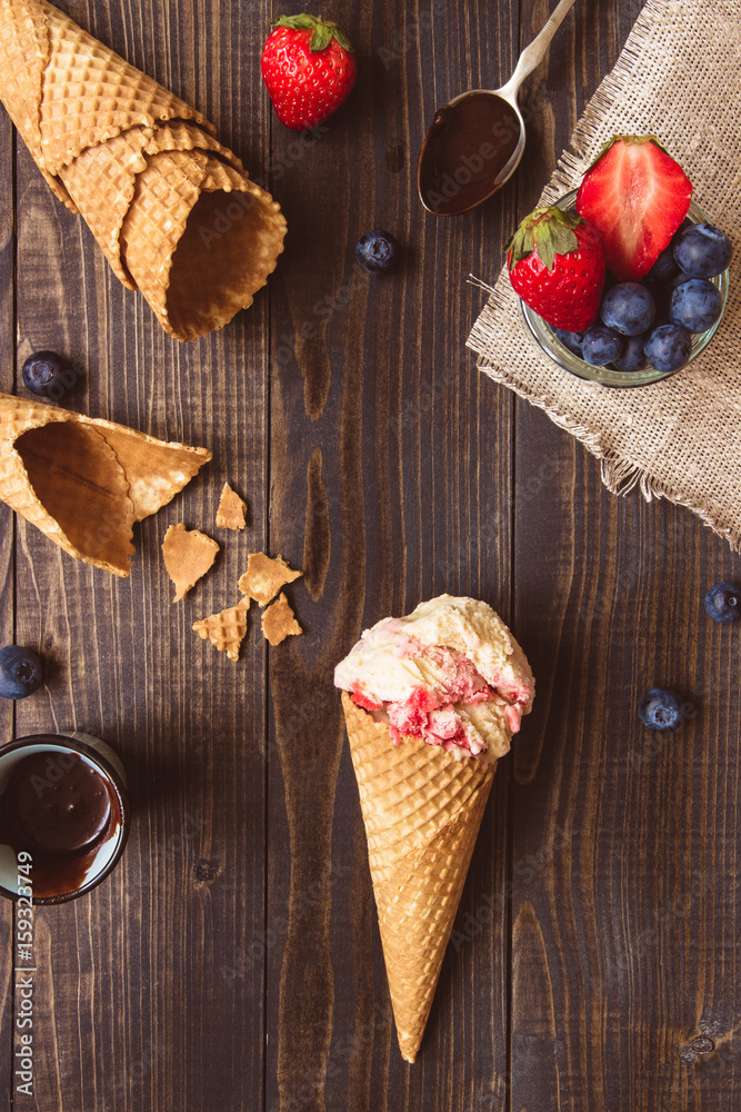 Ice-cream with fresh berries and chocolate sauce on the wooden background, top view Ice-cream with fresh berries and chocolate sauce on the wooden background, top view