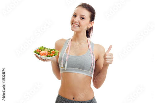 horizontal portrait fun beautiful girl who holds in her hand a plate of vegetable salad and shows a gesture class © ponomarencko