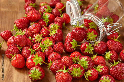 Fresh red strawberries for jam in a glass jar on the brown wooden table. photo