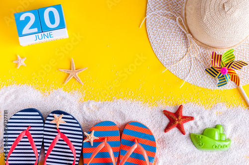 June 20th. Image of june 20 calendar on yellow sandy background with summer beach, traveler outfit and accessories. Summertime concept