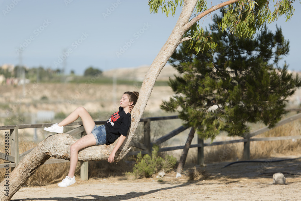 Teenage girl asleep on top of a tree.