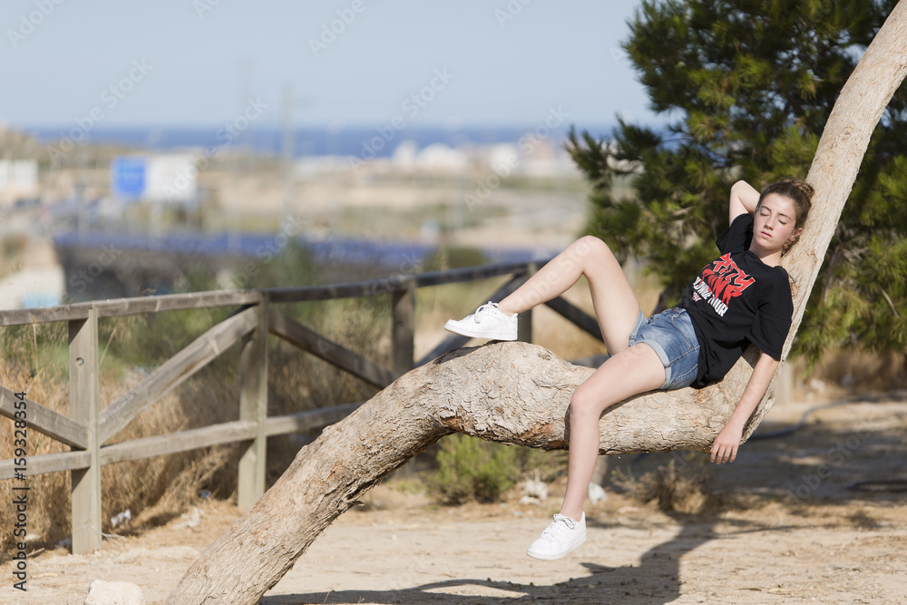 Teenage girl asleep on top of a tree.