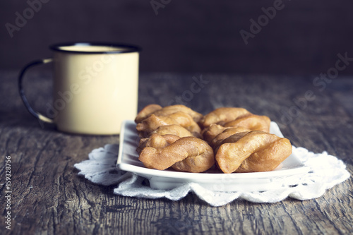 Metal mug full of coffee and a plate of koeksisters in artistic conversion photo