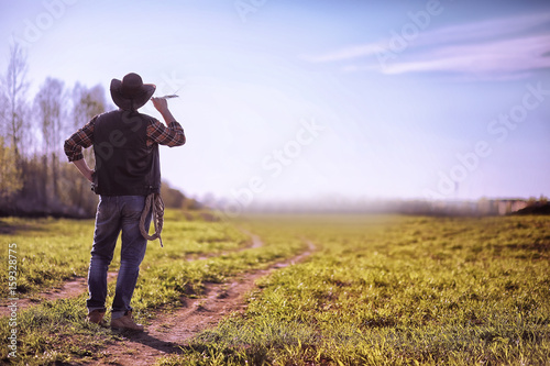 Cowboy standing in a field at sunset © alexkich