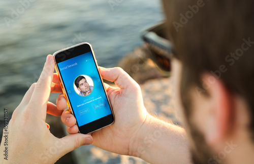 Man receiving invitation his mobile phone on the coast