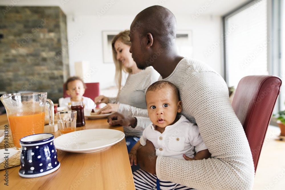 Young interracial family with little children having breakfast. Young interracial family with little children having breakfast.