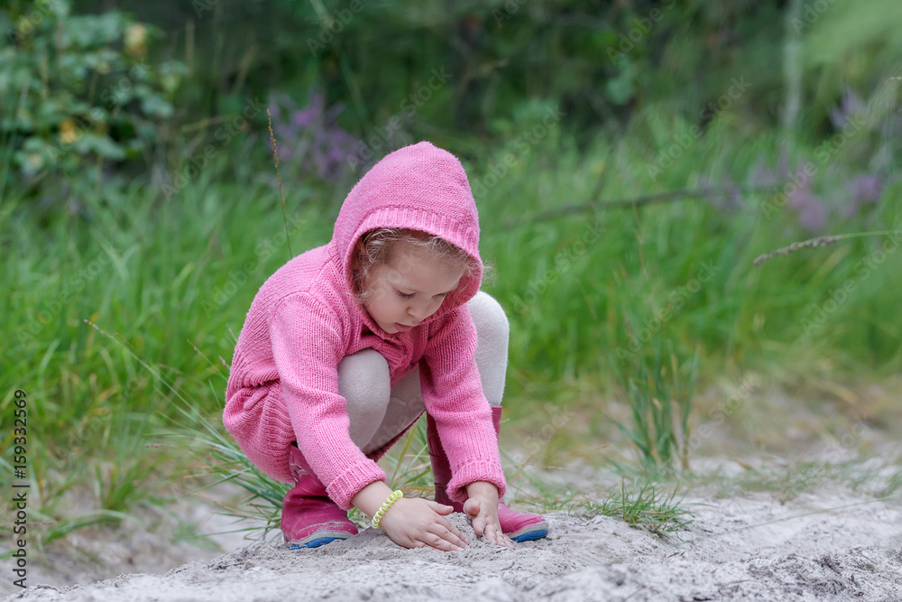Little girl playing with sand in summer forest Little girl playing with sand in summer forest