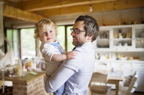 Businessman coming home, holding his son high in the arms.