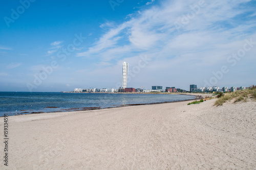 Sea coast with sandy beach near the town of Malmo in Sweden. In the background the city with a tall tower.