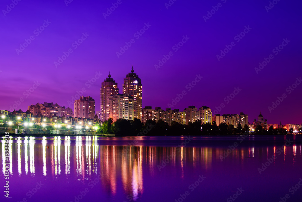 Embankment of modern european city with night illumination and colorful sky. Evening at the Dnieper river in Obolon, Kiev