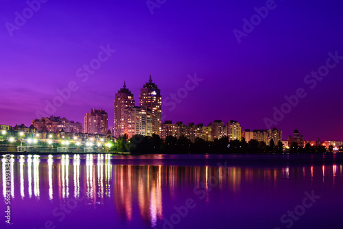 Embankment of modern european city with night illumination and colorful sky. Evening at the Dnieper river in Obolon  Kiev
