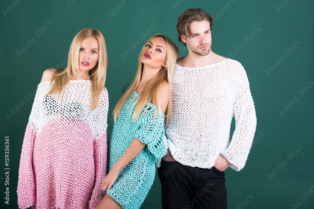 Twin sisters and handsome man posing in sweaters