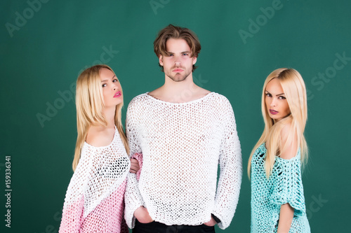 Twin sisters and handsome man posing in sweaters