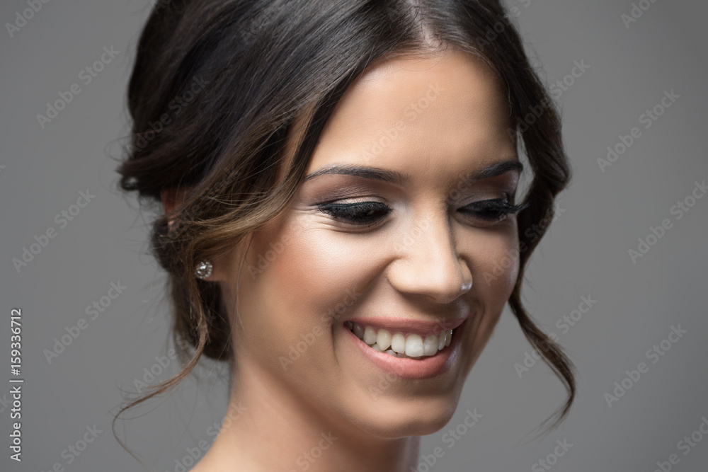 Close up horizontal portrait of shy timid girl blush smiling and looking down over gray studio background. Close up horizontal portrait of shy timid girl blush smiling and looking down over gray studio background.