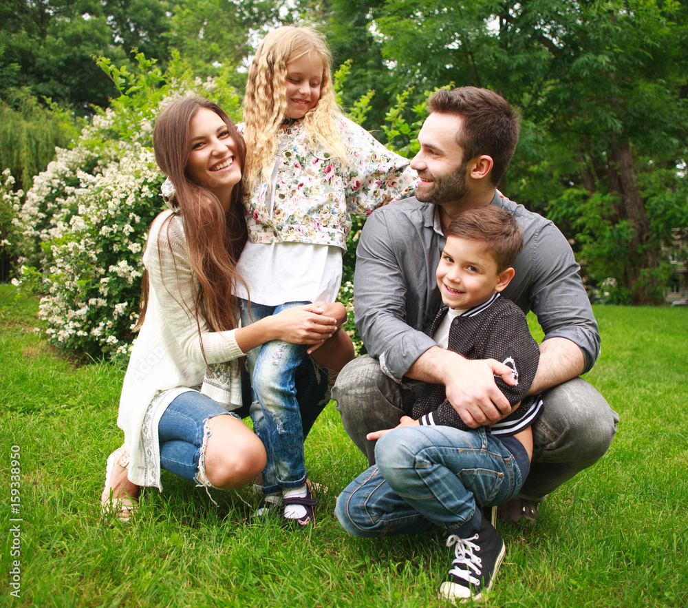 Fototapeta premium Young happy family with two children in summer green park