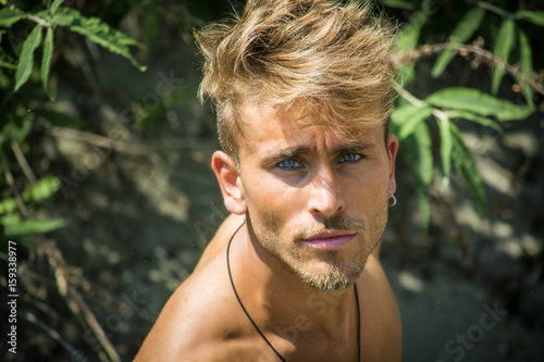 Fotografija Head and shoulders shot of shirtless blond young man seen from above, looking at