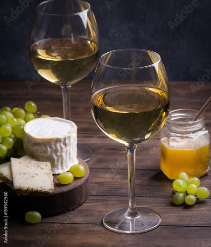 Various sorts of cheese, grapes and two glasses of the white wine