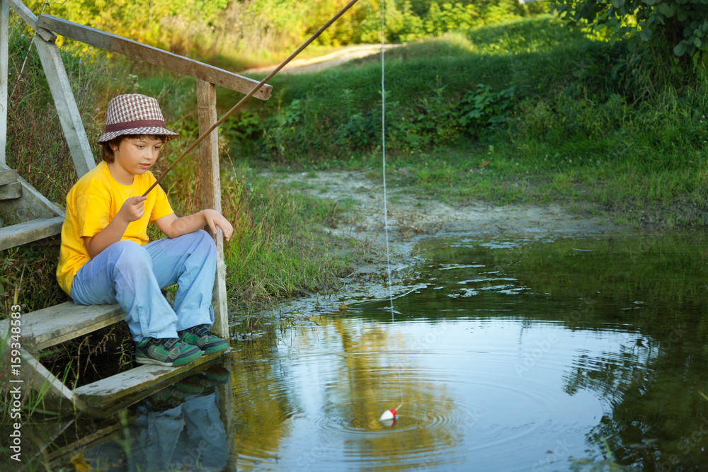 Happy boy go fishing on the river, one children fisherman with a fishing rod on the shore of lake Happy boy go fishing on the river, one children fisherman with a fishing rod on the shore of lake