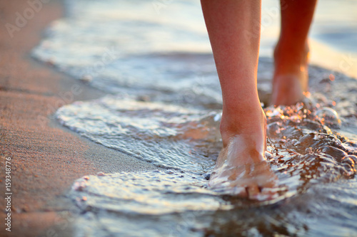 Female feet step on the sea wave photo