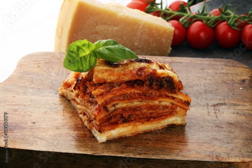 Serving of spicy traditional Italian beef lasagne in a restaurant - bolognese sauce topped with basil leafs