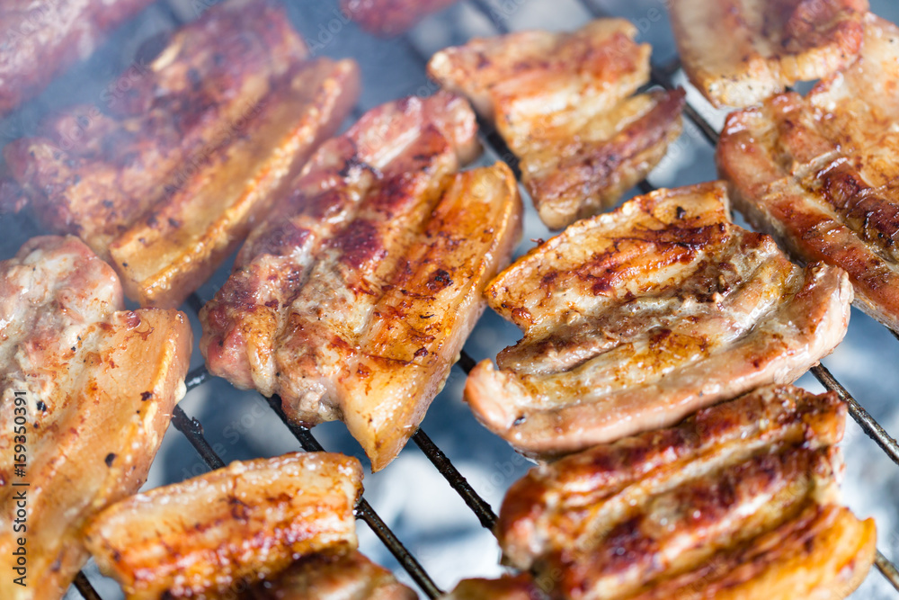 Grilled pork belly, bacon on hot grate close up