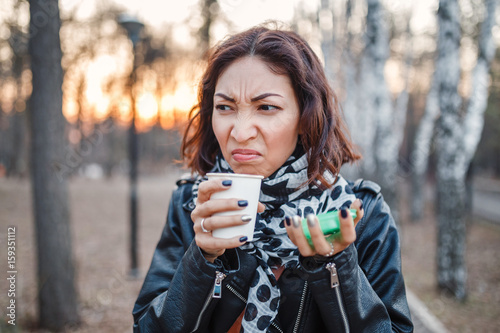 Foto Shocked woman tries disgusting coffee or tea from a disposable takeaway coffee o