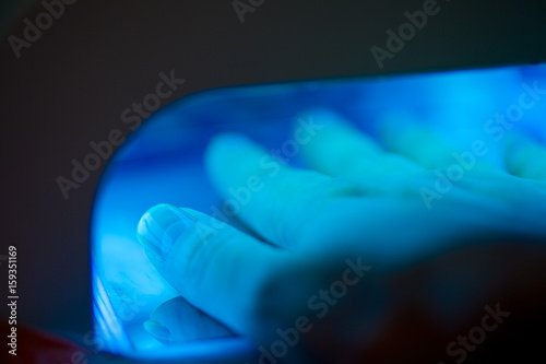 Manicure process concept. Female hand inside lamp for nails.