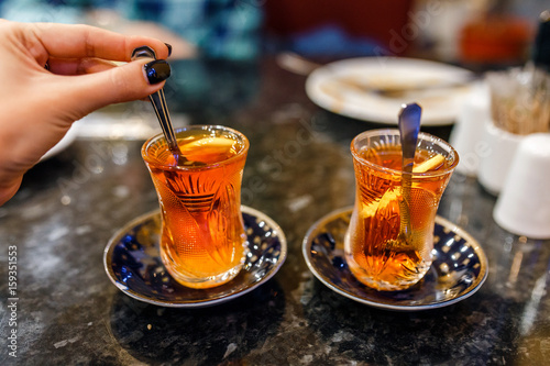 Turkish tea with traditional tea glass in cafe, with female hand at foreground photo