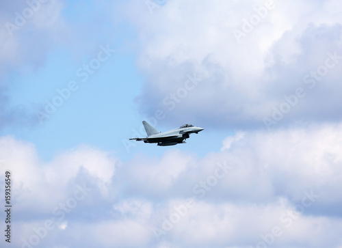 Jet fighter against the cloudy and blue sky.