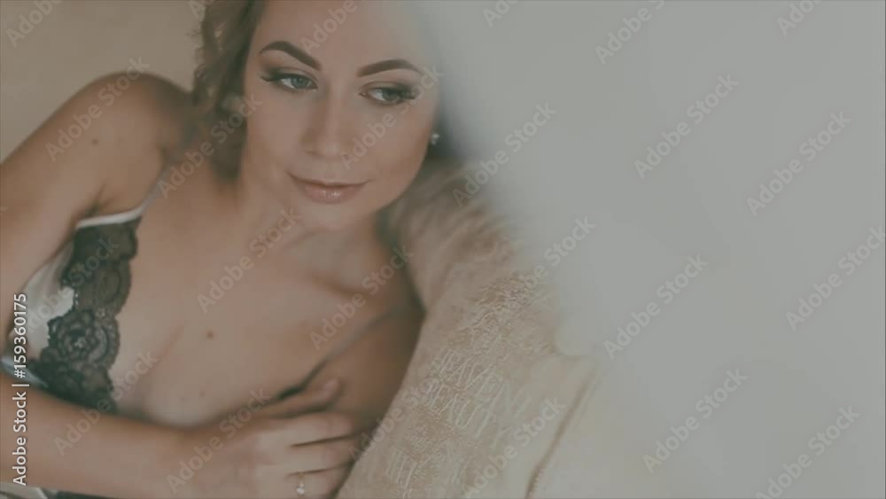 Beautiful bride in white lingerie sitting on bed in her bedroom and putting on stockings Beautiful bride in white lingerie sitting on bed in her bedroom and putting on stockings