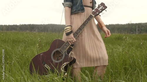 Unrecognizable woman with guitar on field
