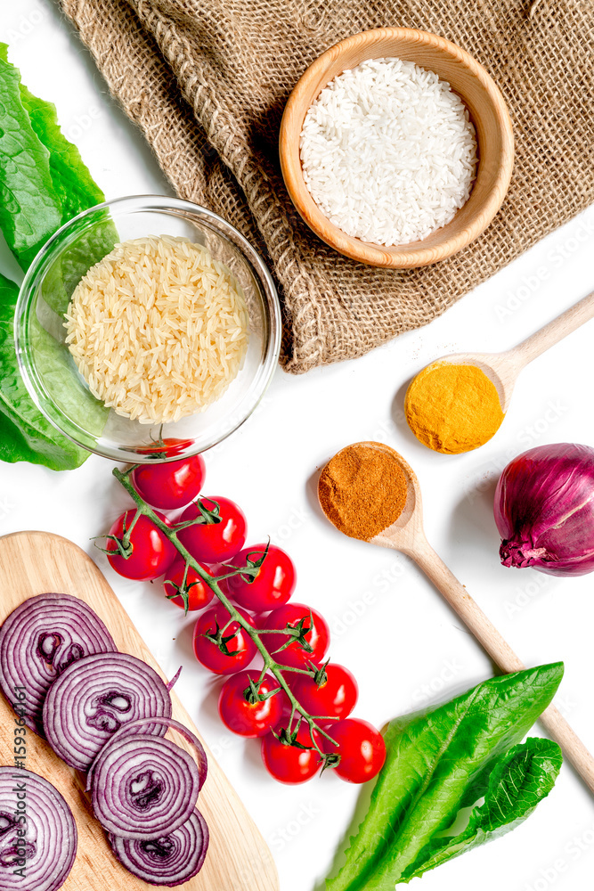 homemade paella ingredients composition with rice, tomato, onion on white table background top view