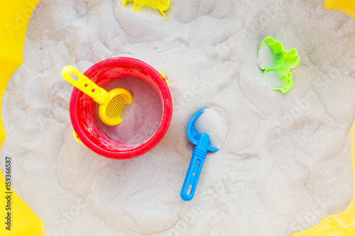 Obraz na plátně Plastic bucket, sifter and a small shovel in the sand; view from above