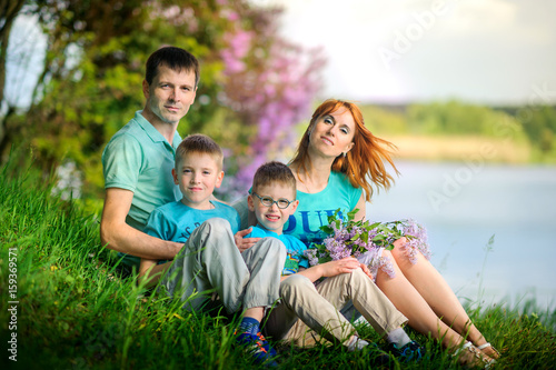 happy family on walk in the park  sit on the river bank with a bouquet of flowers in hands