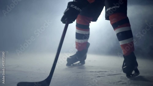 Hockey player hits the puck with a stick on ice close-up