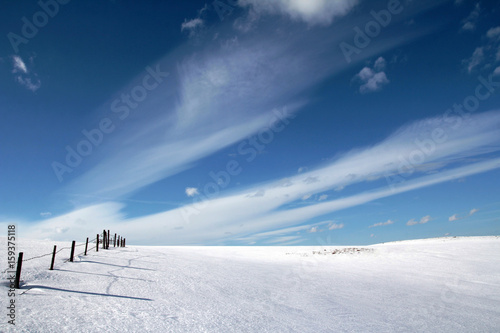 Verschneiter Viehzaun unter weiß-blauem Himmel