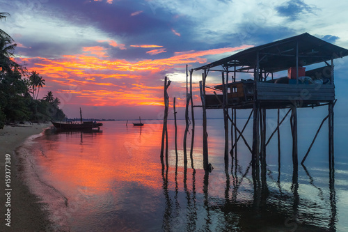 Romantic scenery of sunset on the beach in Asia with house and boat silhouette.