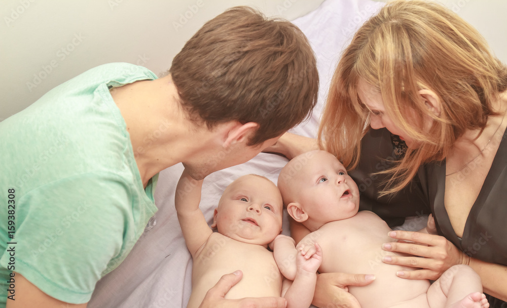 indoor portrait of young happy smiling mother and father with twin babies at home indoor portrait of young happy smiling mother and father with twin babies at home