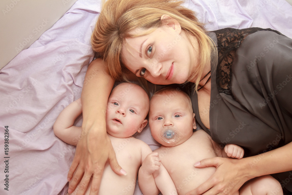 indoor portrait of young happy smiling mother with her twin babies at home indoor portrait of young happy smiling mother with her twin babies at home