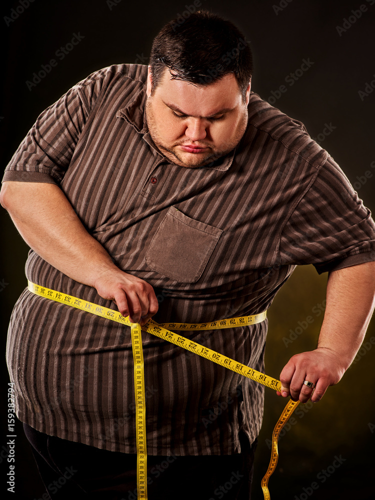 Man belly fat with tape measure weight loss around body on black