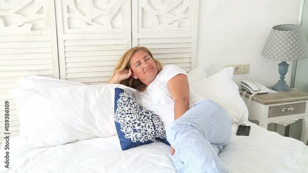 Portrait of a blond woman laying on a bed and daydreaming Portrait of a blond woman laying on a bed and daydreaming
