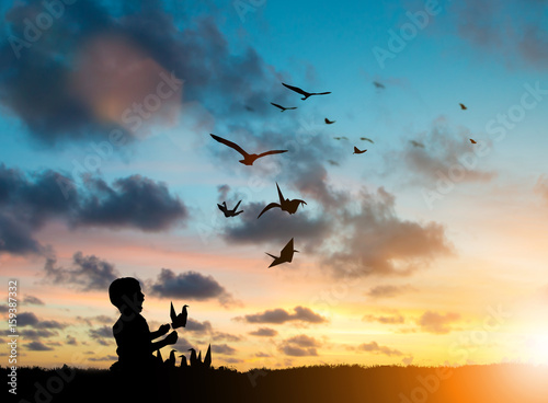 Silhouette Children playing paper birds that fly with real birds freely over blurred natural. Imagination is more important to the development of children s brains. Learning and freedom concept.