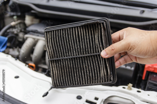 Technician holding dirty air filter for car