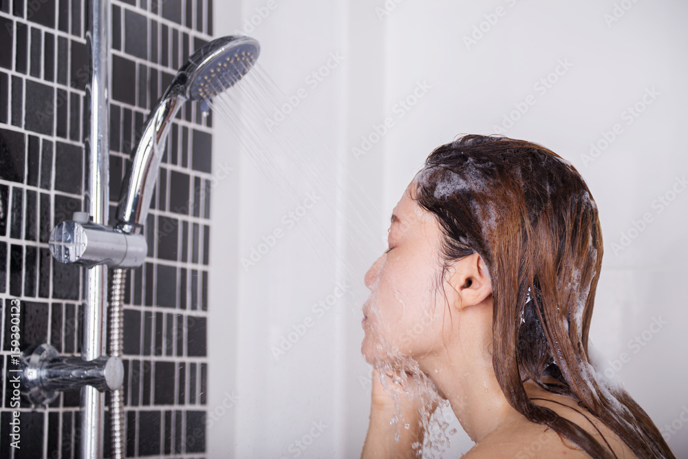 Woman is washing her face by shower Woman is washing her face by shower