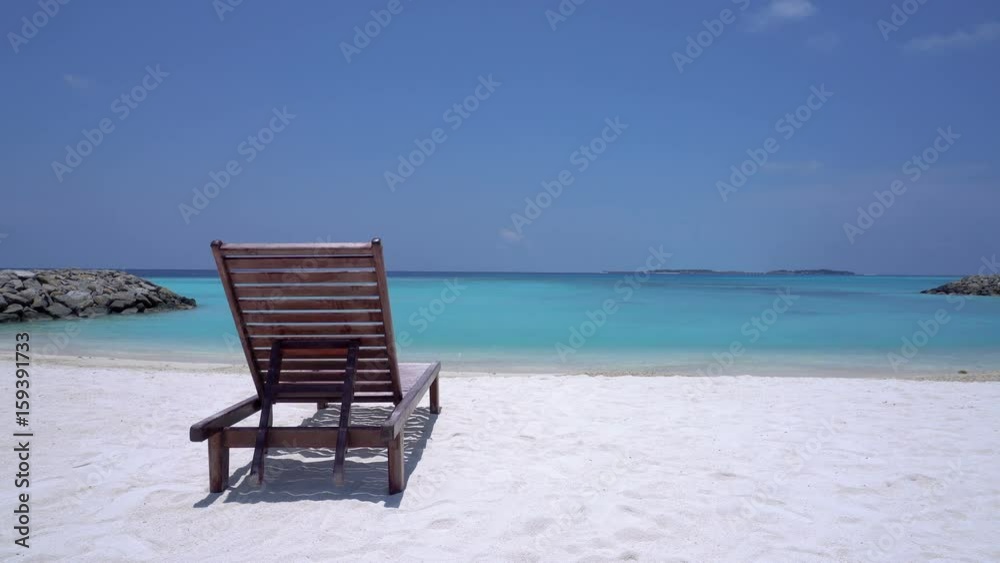 One wooden sunbed on tropical calm beach with turquoise sea water and white sand
One wooden sunbed on tropical calm beach with turquoise sea water and white sand