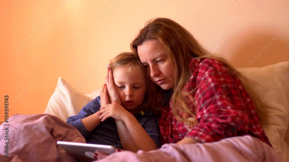 mother and child using tablet in bed before going to sleep mother and child using tablet in bed before going to sleep