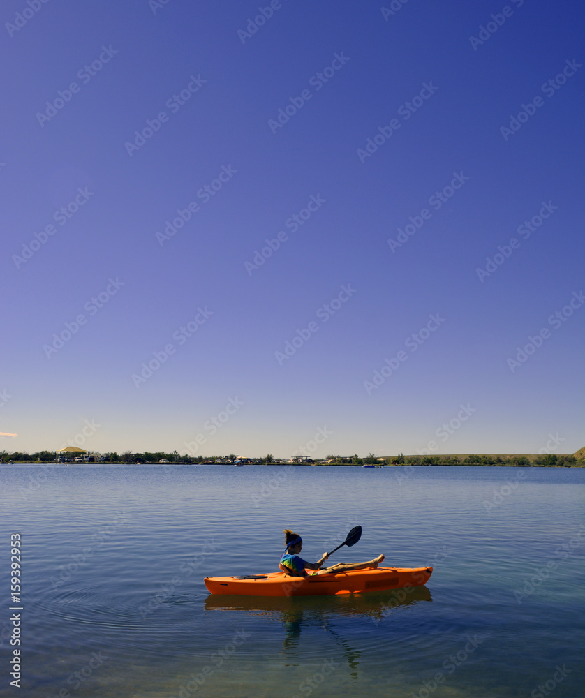 Teen Kayaking/Teenage girl paddling kayak on a calm lake. 